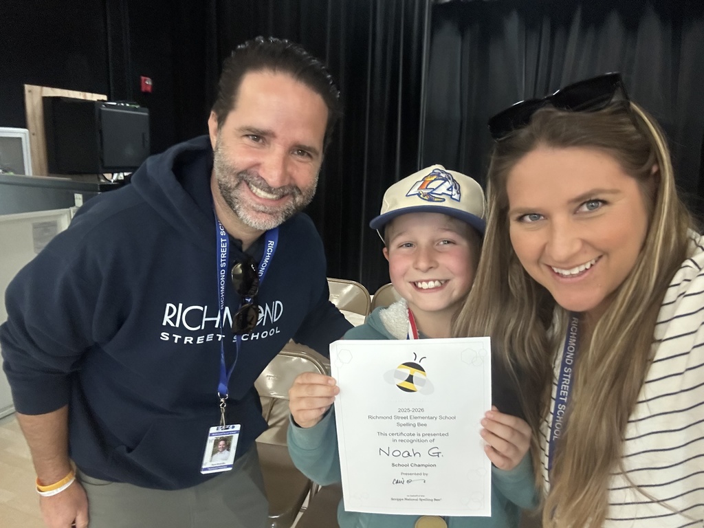 Noah, the spelling bee champion, poses proudly with his certificate and medal alongside two smiling Richmond Street School staff members.