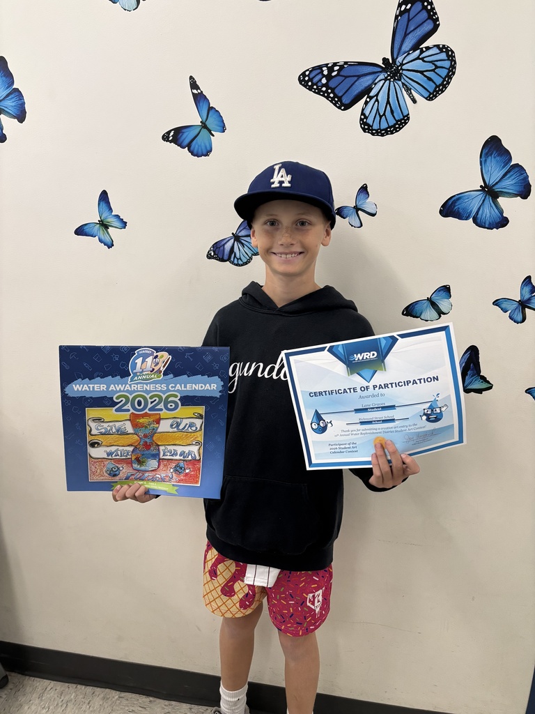 Child wearing a blue LA cap and colorful shorts holds a 2026 Water Awareness Calendar and a Certificate of Participation against a wall decorated with blue butterfly decals.