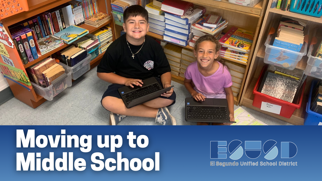 Two children sitting on the floor in a classroom surrounded by bookshelves, each using a laptop for schoolwork.