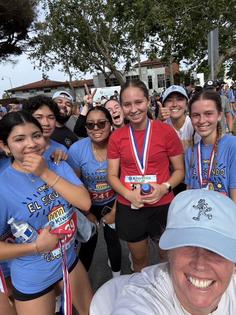Group of runners wearing medals and race bibs after completing a community race event outdoors.