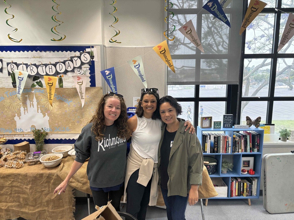 Three staff members pose together beside Disney-themed decorations during a teacher appreciation celebration.