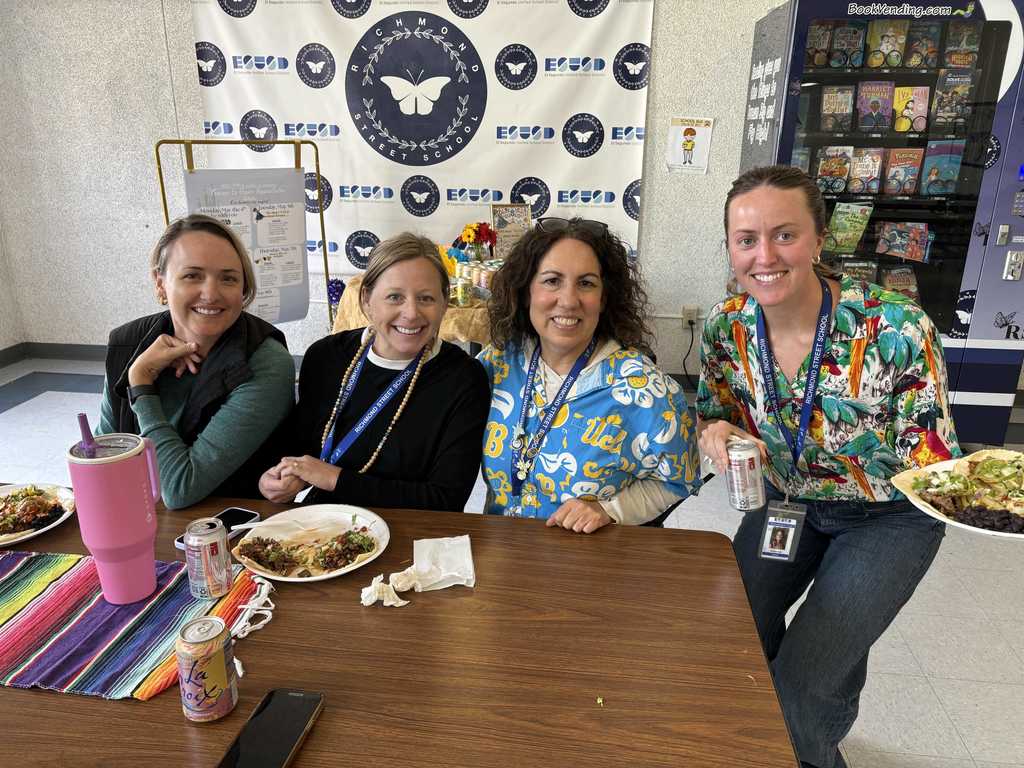 Four Richmond Street School staff members sit together enjoying tacos and drinks during a festive lunch celebration.