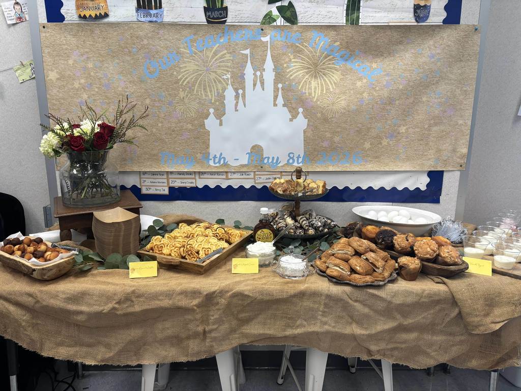 Teacher appreciation breakfast spread with pastries, fruit, and flowers beneath a “Our Teachers are Magic” display.