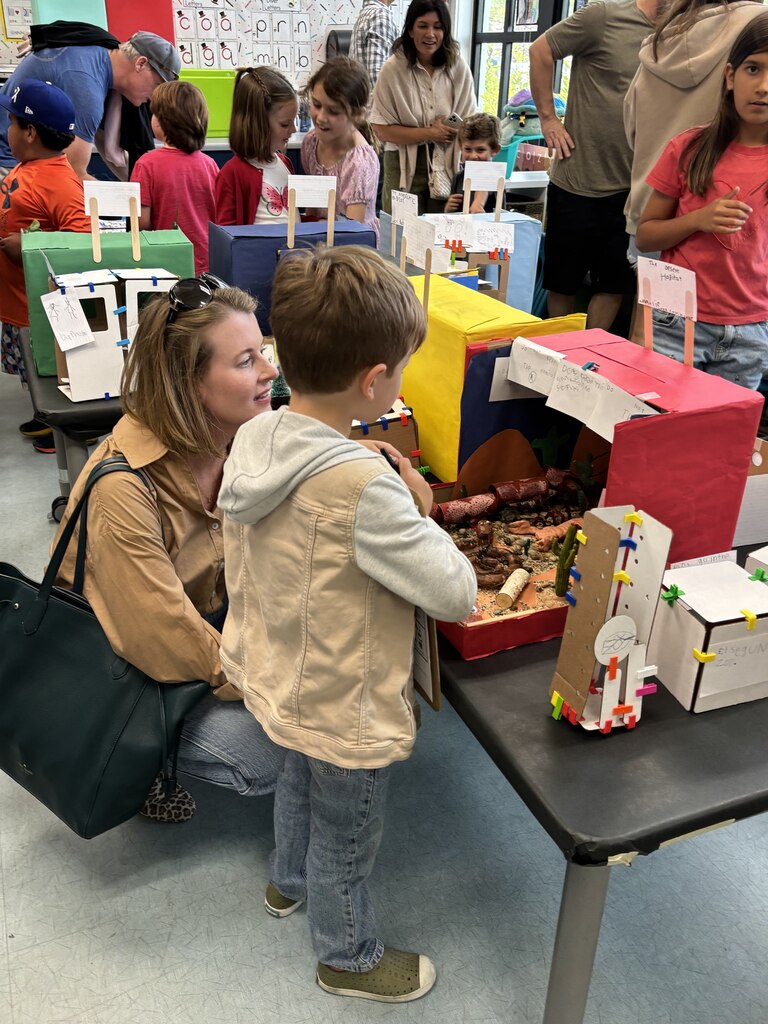 Families and students gather around colorful student-made projects during a busy elementary classroom open house. Families and students gather around colorful student-made projects during a busy elementary classroom open house.