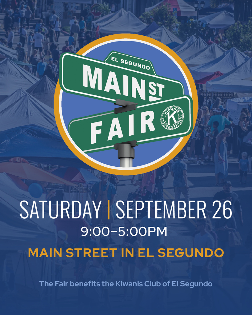 Street signs reading Main St and Fair at the El Segundo Main Street Fair event with tents and crowds in the background.