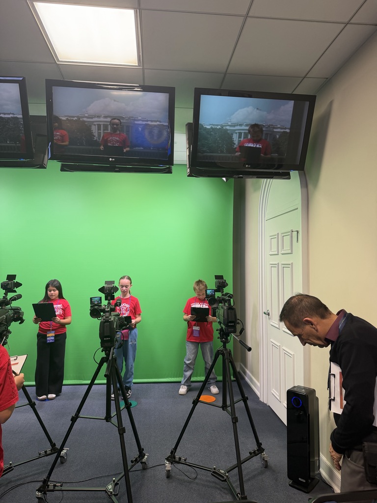 Students practice reading news scripts in front of a green screen, surrounded by professional cameras and monitors.