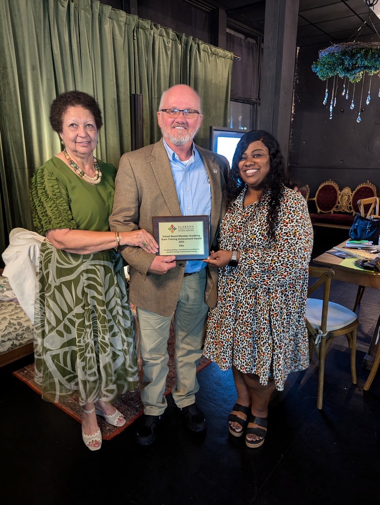 A picture of 3 people in front of a curtain accepting an award.