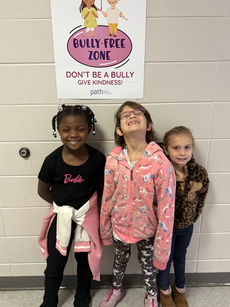 3 Students standing in front of a background.