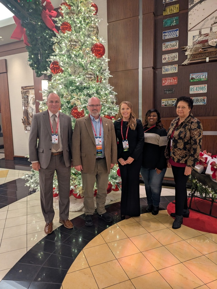 A group of people standing in front of a Christmas tree.