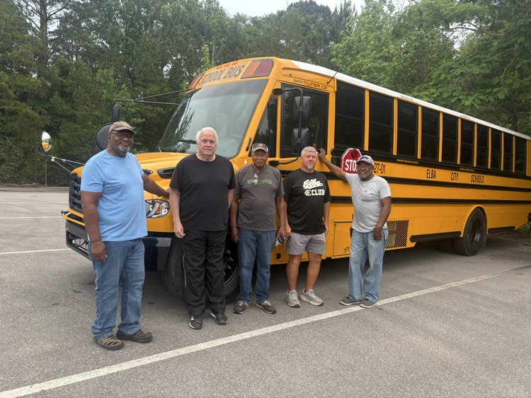 Five men in front of a bus.