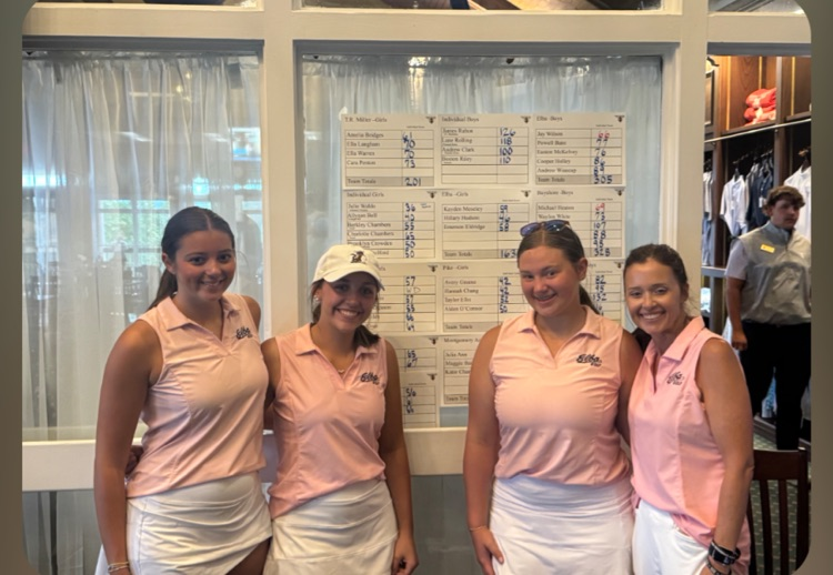 A group of girls standing in front of a scoreboard .