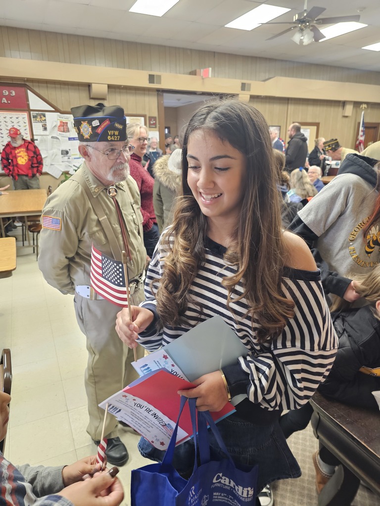 A student hands out hand-held American Flags at a Veterans Day event