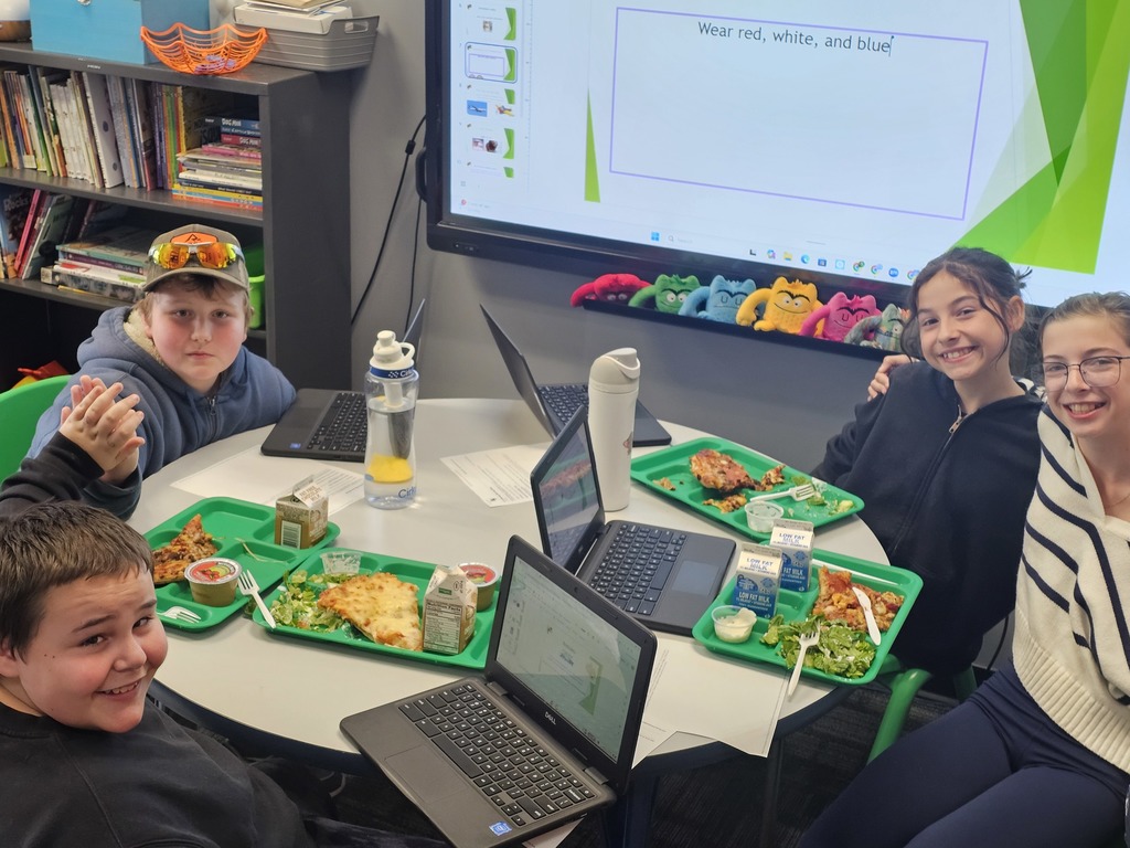 Image of the 6th grade media production group having a working lunch meeting preparing for the next week's Beginning Buzz