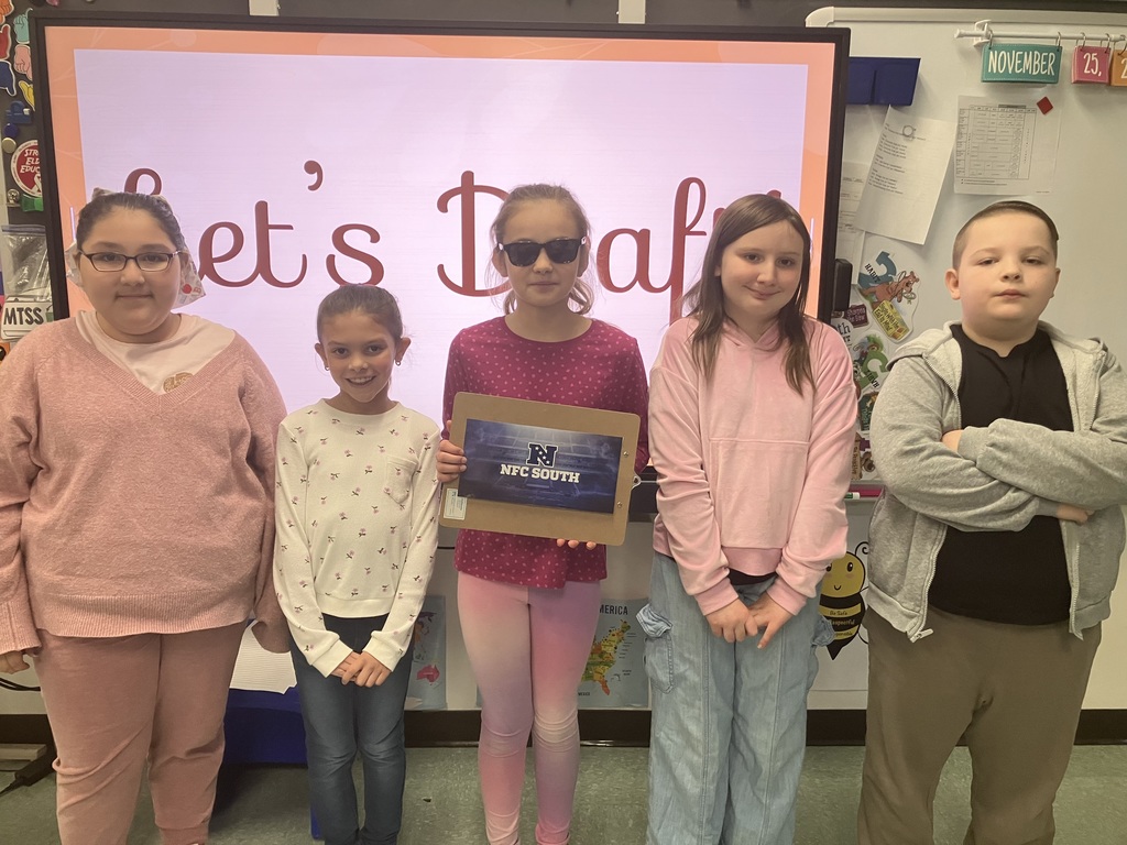 Image of students on "draft day" for their NFL fantasy football reading challenge posing with their team