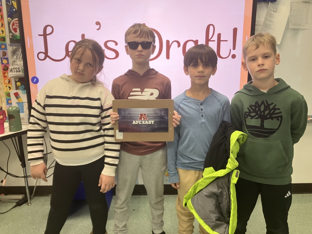 Image of students on "draft day" for their NFL fantasy football reading challenge posing with their team