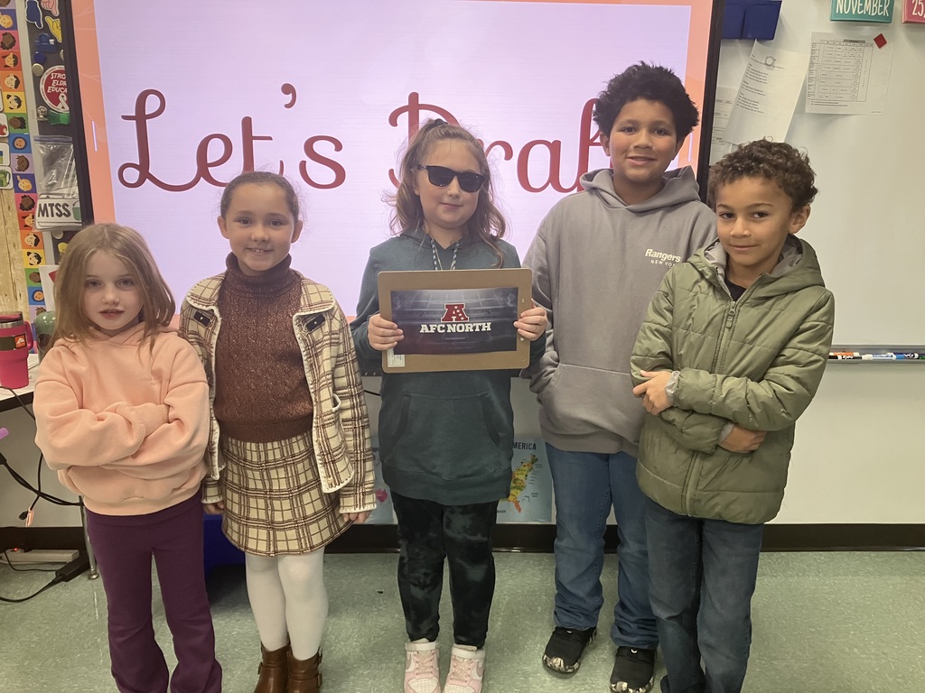 Image of students on "draft day" for their NFL fantasy football reading challenge posing with their team