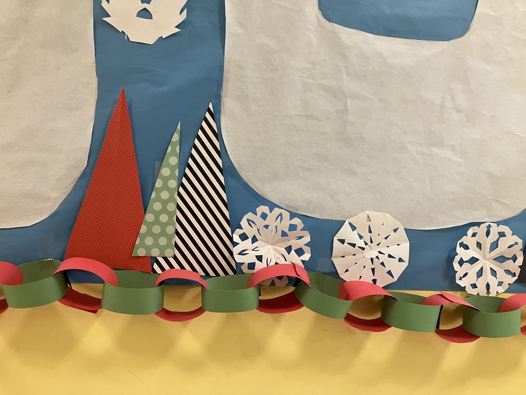 Colorful paper trees and hand-cut snowflakes decorate a bulletin board