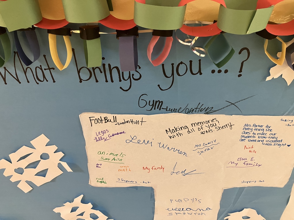 details on a bulletin board paper chains, paper lights, hand-cut snowflakes, handwritten things that bring people joy