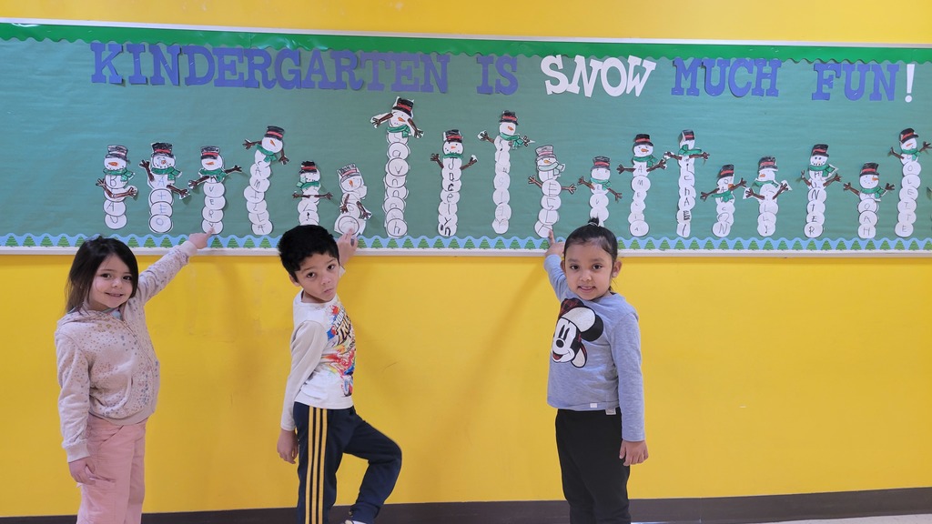 Students point to their names on a snowman bulletin board