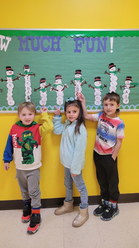 Students point to their names on a snowman bulletin board