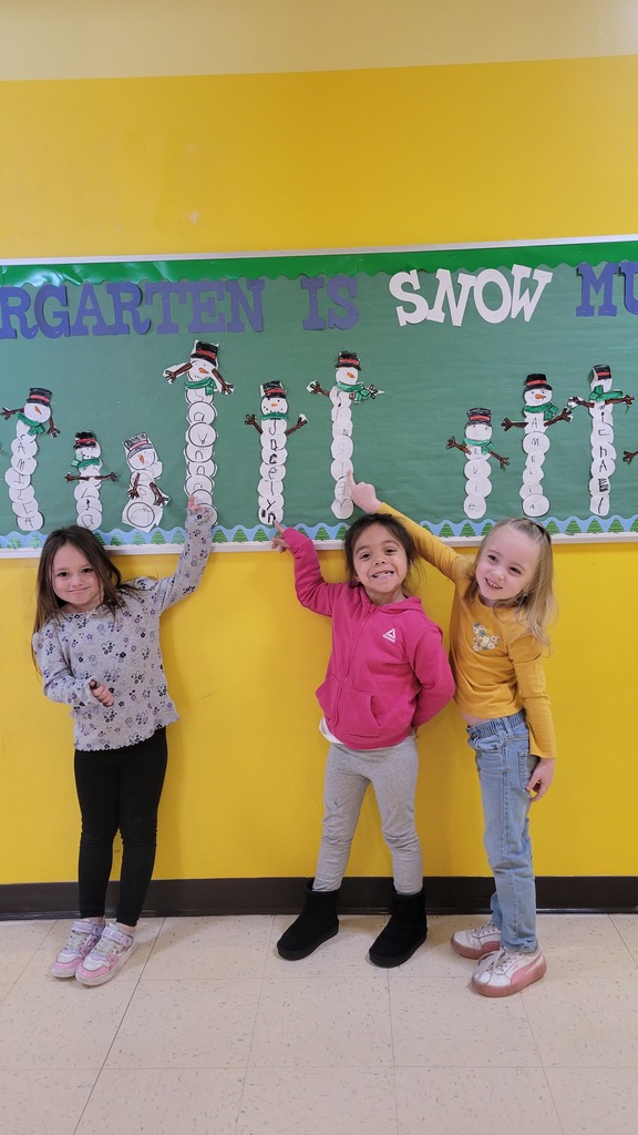 Students point to their names on a snowman bulletin board