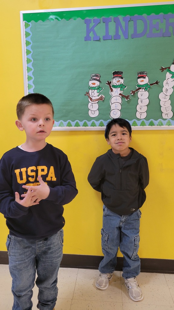 Students stand in front of a snowman bulletin board