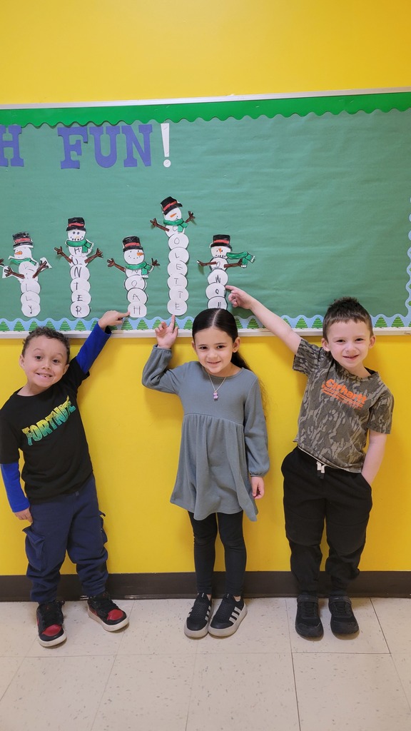 Students point to their names on a snowman bulletin board