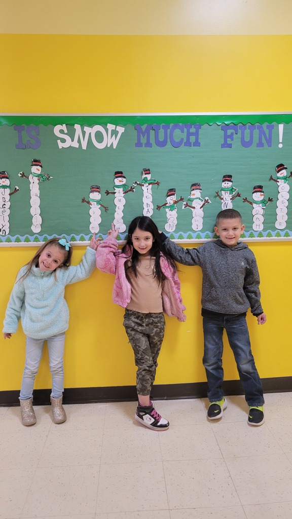 Students point to their names on a snowman bulletin board
