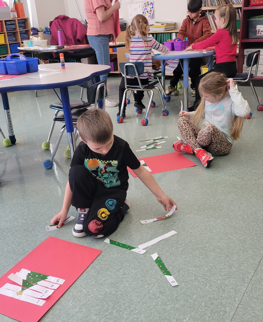 A student sits on the floor working on sequencing a Christmas Tree project