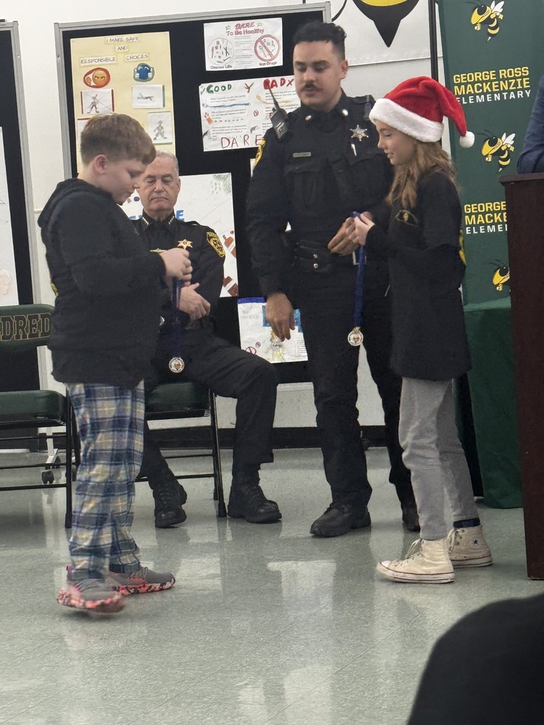 Image of students receiving their DARE coins from the School Resource Officer