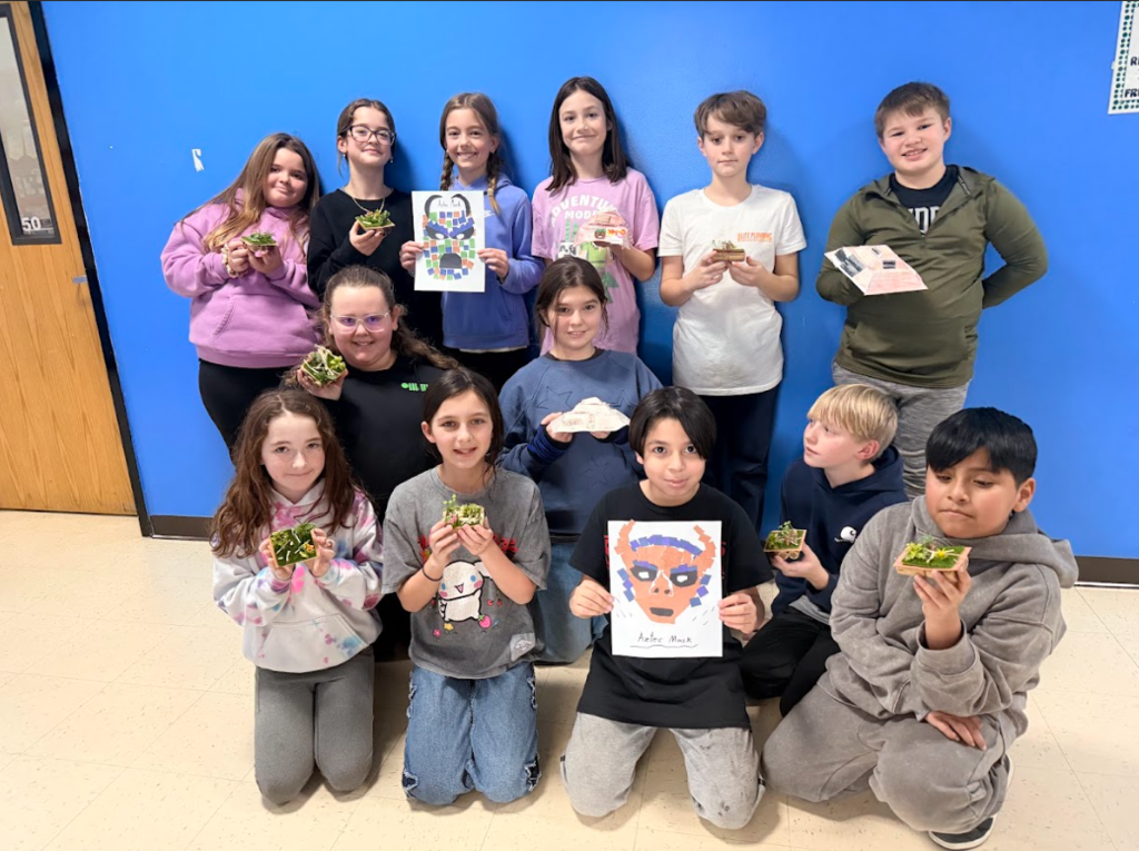 image of a class with their projects for their ancient civilizations unit holding ancient masks, Chinampas (floating gardens) and 3D pyramids