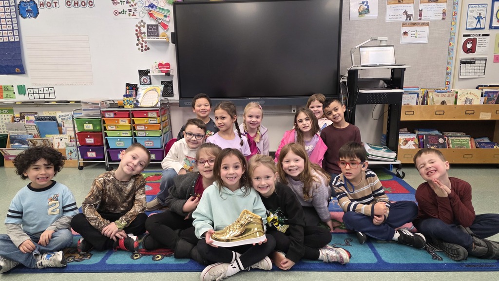 Image of student holding a golden shoe, their reward for good behavior in the hallways