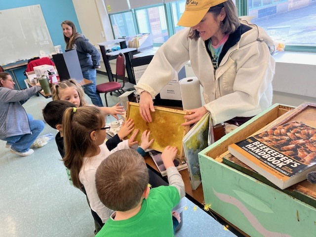 Students are engaged with an adult showing them a honeycomb 