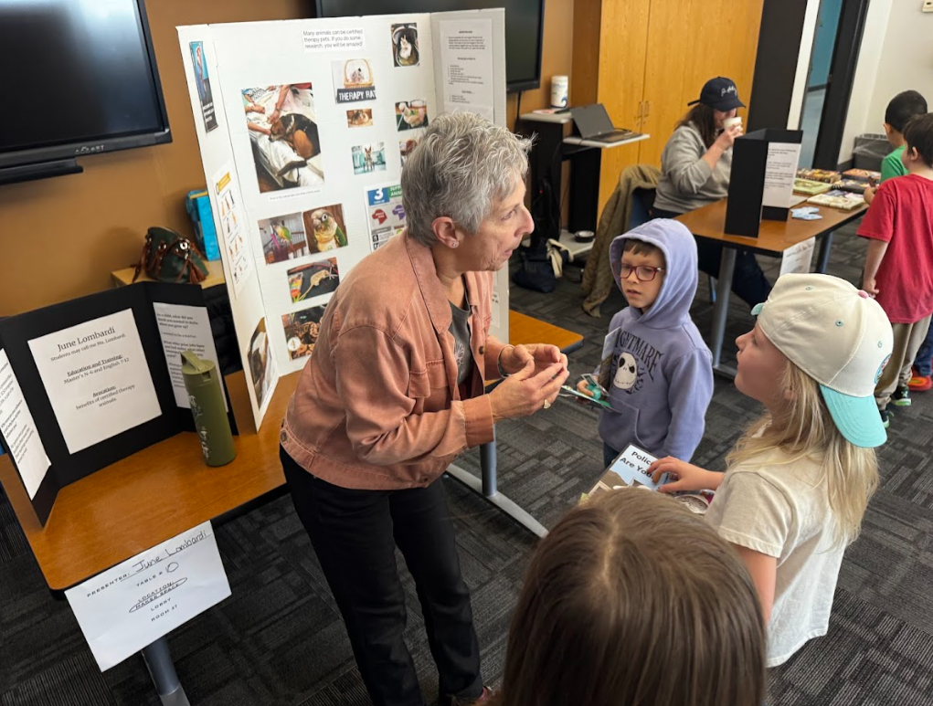 An adult is speaking to a group of school children about therapy animals