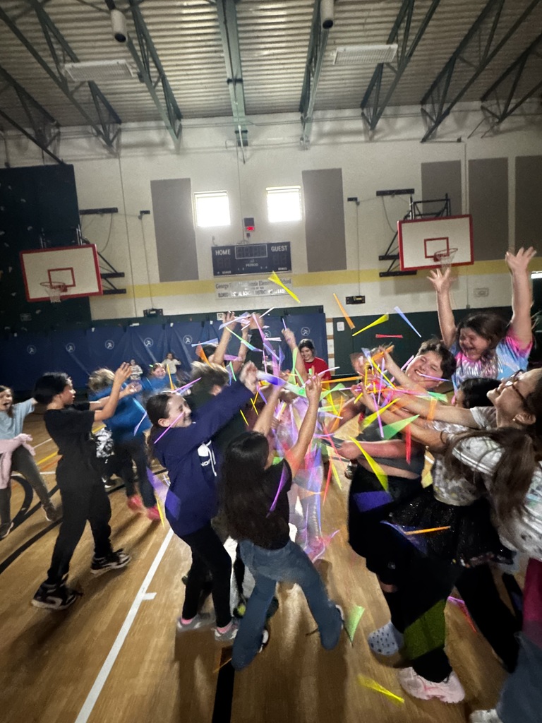 Students huddle together  and throw glow sticks in air