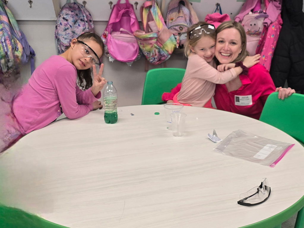 Students pose for the camera wearing safety goggles for a science experiment