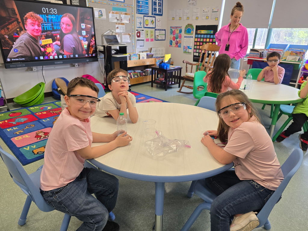 Students pose for the camera wearing safety goggles for a science experiment