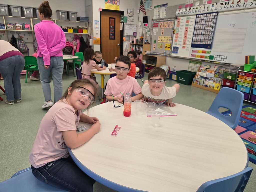 Students pose for the camera wearing safety goggles for a science experiment