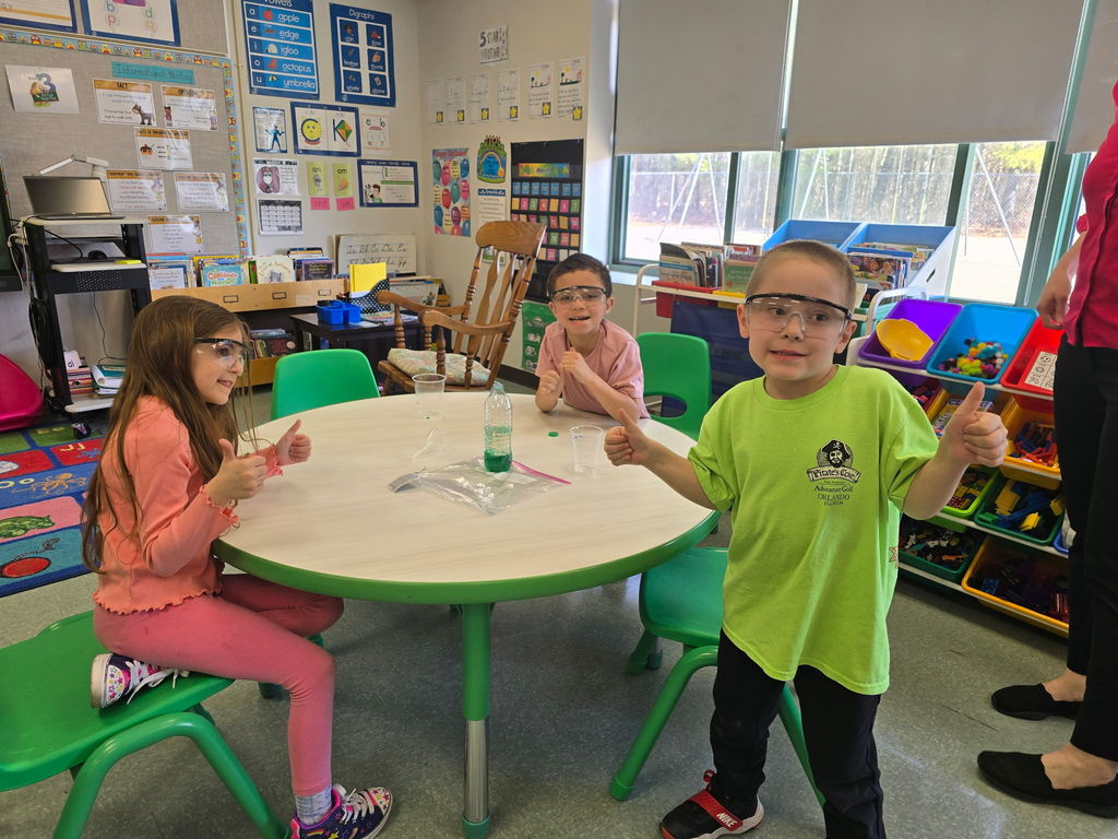 Students pose for the camera wearing safety goggles for a science experiment