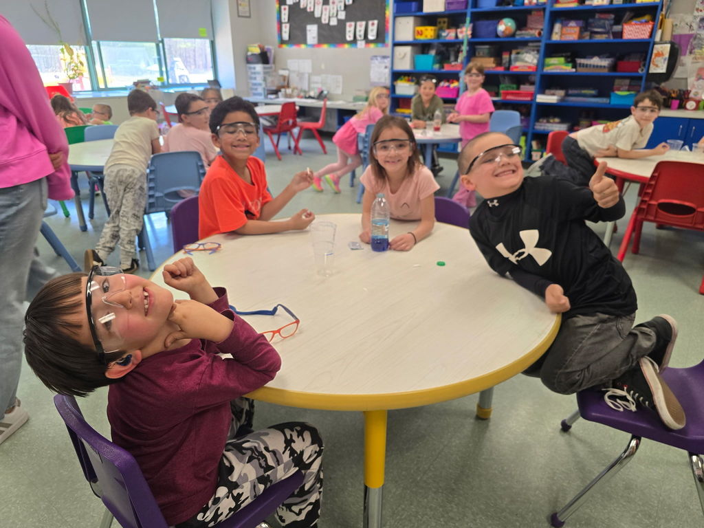Students pose for the camera wearing safety goggles for a science experiment