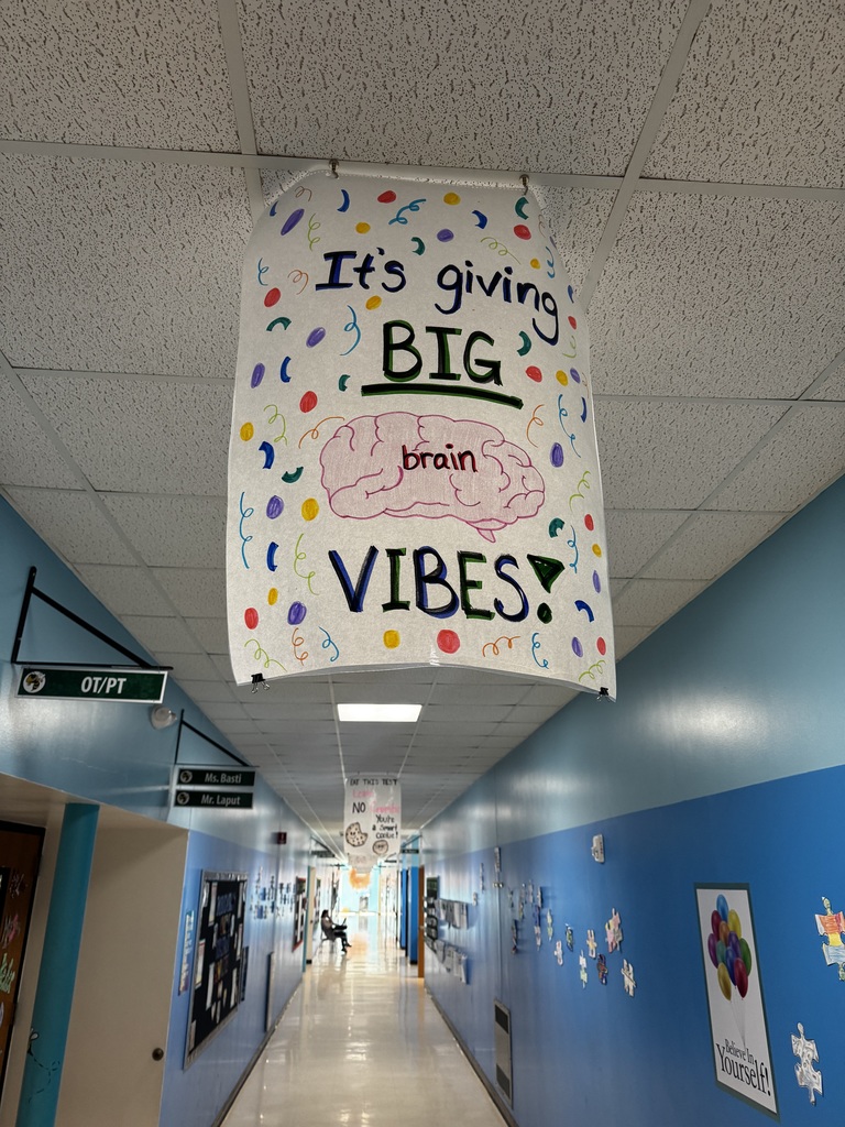Image of a poster hanging from the ceiling of a school hallway that reads " It's Giving Big Brain Vibes!"