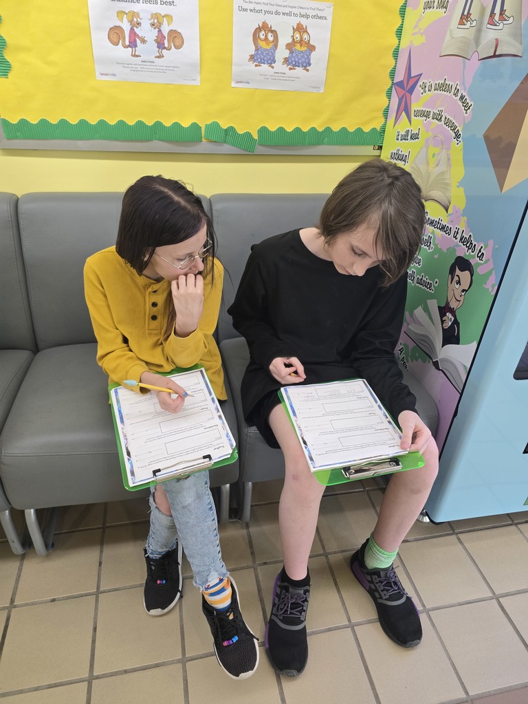 Image of two students sitting on a couch figuring out math problems on the clipboards