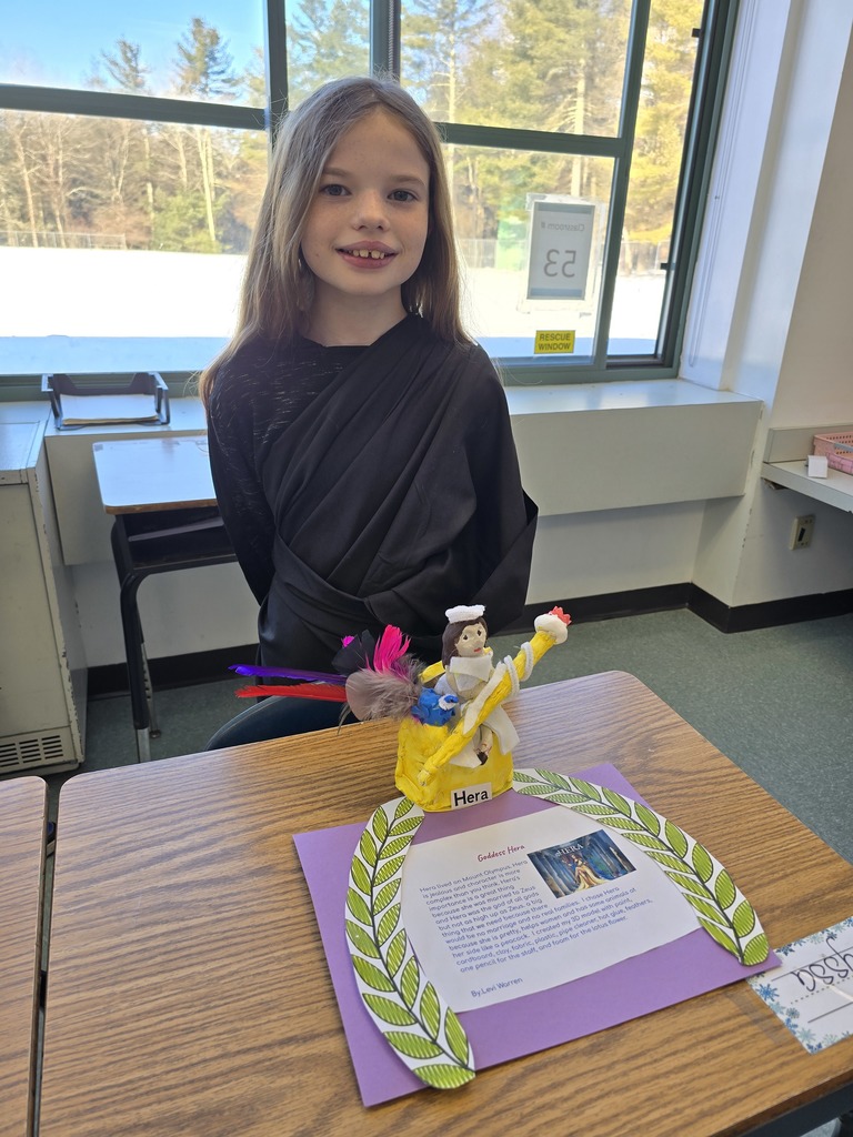 Image of a student in a toga made of a black bed sheet standing behind her Greek Mythology project about Hera