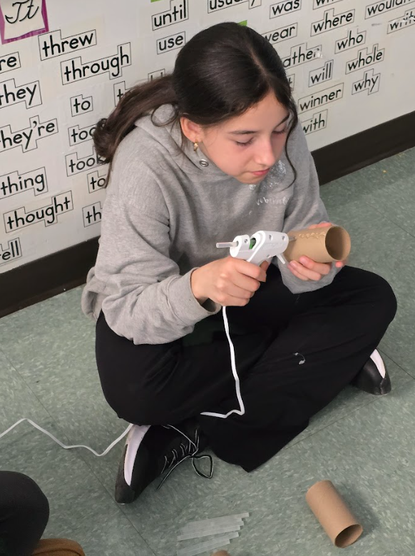 A student volunteers her time to create cat enrichment toys out of toilet paper rolls for an animal rescue