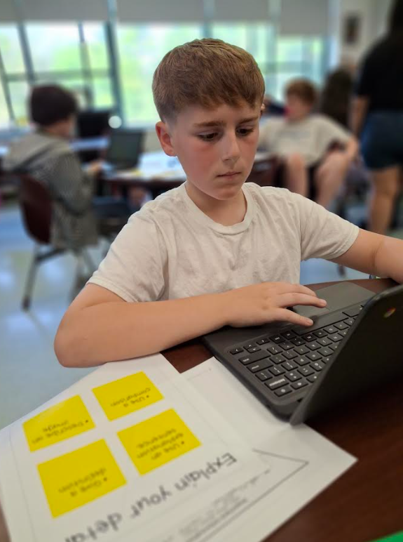 Image of a student on his Chromebook working on a writing assignment