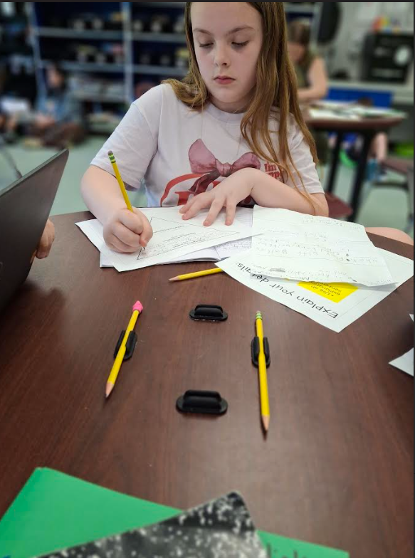 Image of a student sitting at her desk working on a writing assignment