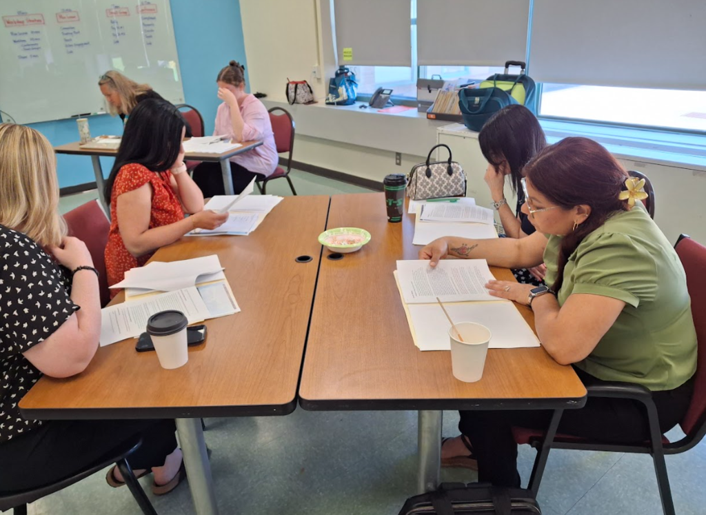 Educators sit at desks looking over materials in a professional development session
