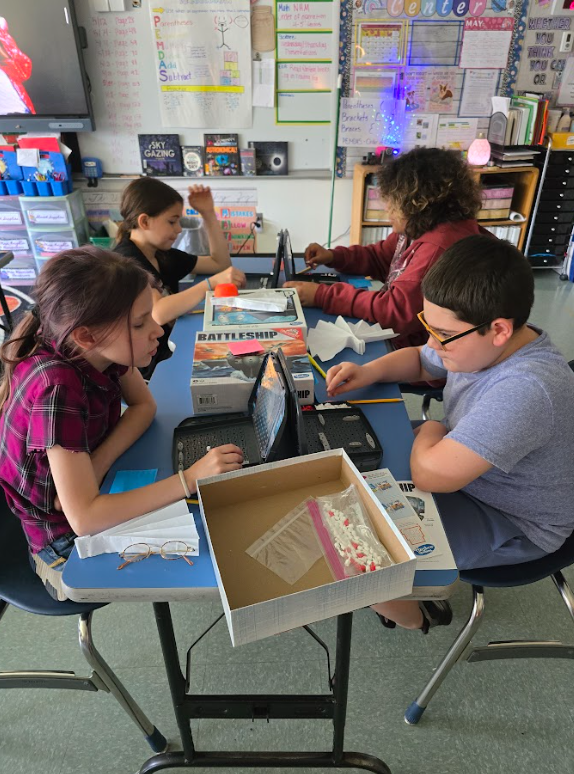 Image of students sitting at a table playing a game of Battleship
