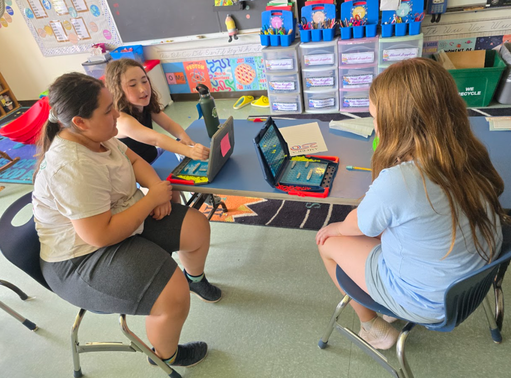 Image of students sitting at a table playing a game of Battleship