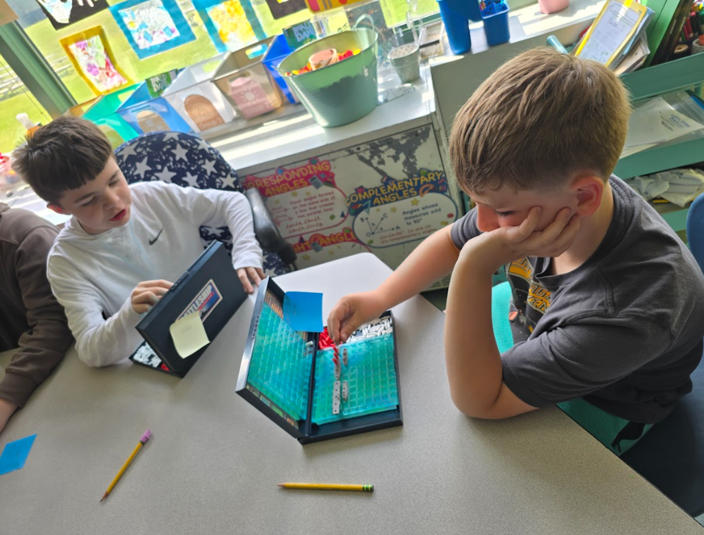 Image of students sitting at a table playing a game of Battleship